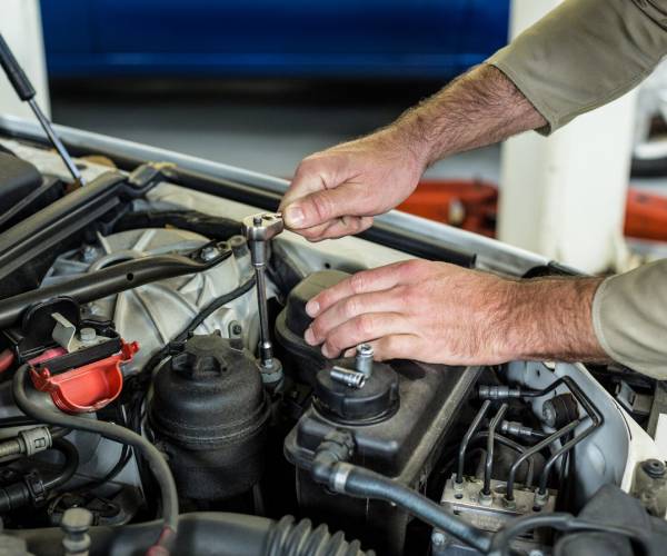 Mechanic servicing a vehicle engine with a socket wrench